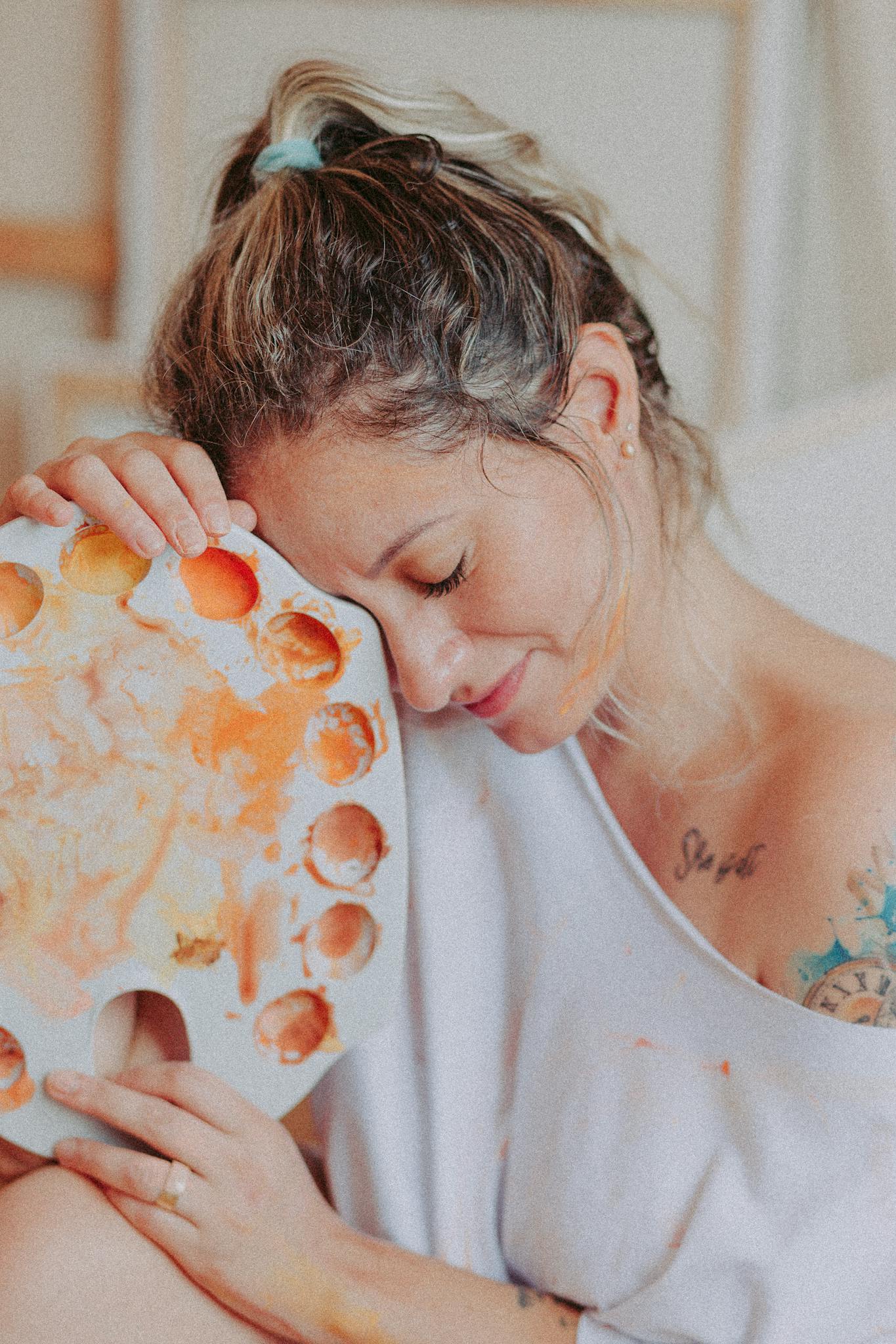 Serene artist enjoying a creative moment with a colorful palette indoors.